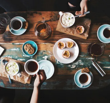 person sitting near table with teacups and plates