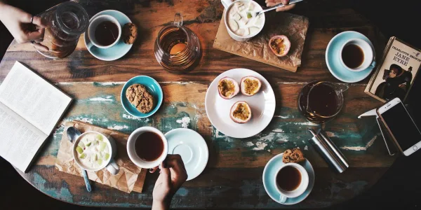 person sitting near table with teacups and plates